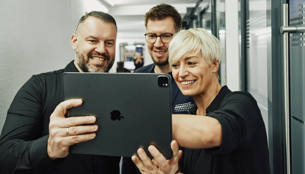 Drei arvenio Mitarbeiter vor einem Tablet-PC